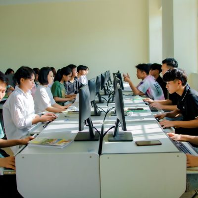 Estudantes participam de uma aula de computação e realizam atividades em computadores.