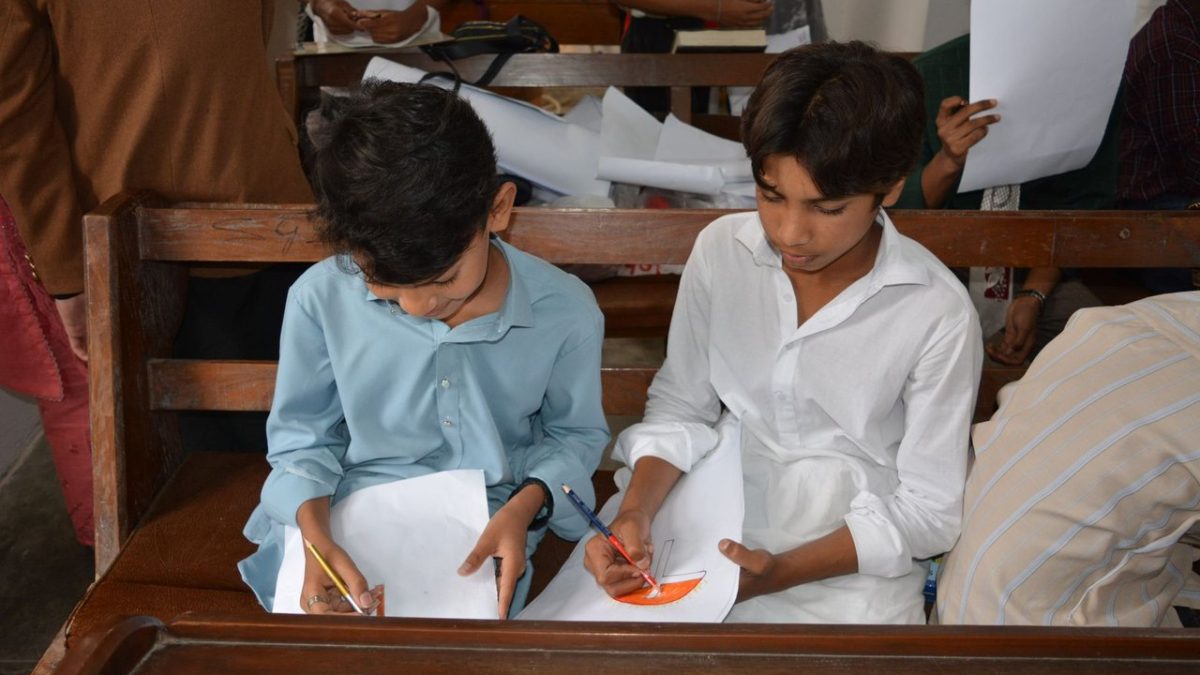 Crianças desenham durante uma aula de educação religiosa dentro de uma igreja.