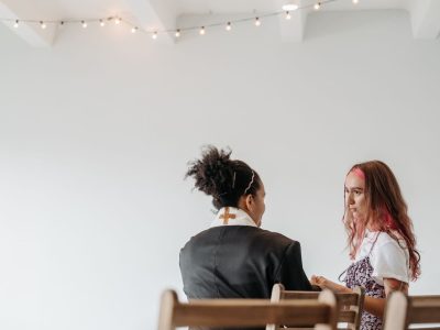 Pastora conversa com outra mulher em um ambiente tranquilo de uma igreja.