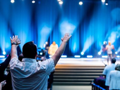 Grupo de pessoas participa de um culto em um auditório moderno.