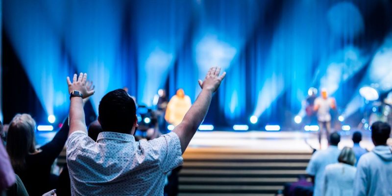 Grupo de pessoas participa de um culto em um auditório moderno.