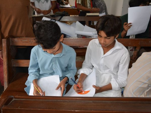Crianças desenham durante uma aula de educação religiosa dentro de uma igreja.