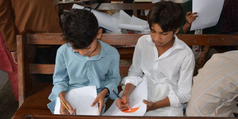 Crianças desenham durante uma aula de educação religiosa dentro de uma igreja.