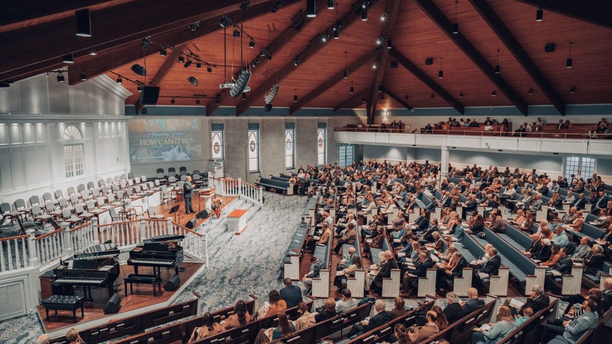Grande público acompanha uma conferência em um auditório moderno de igreja.