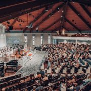 Grande público acompanha uma conferência em um auditório moderno de igreja.