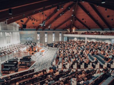 Grande público acompanha uma conferência em um auditório moderno de igreja.