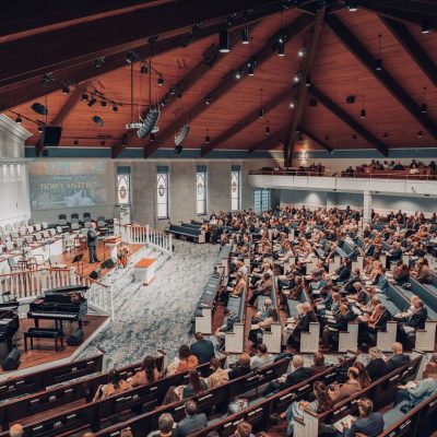 Grande público acompanha uma conferência em um auditório moderno de igreja.