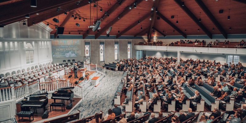Grande público acompanha uma conferência em um auditório moderno de igreja.
