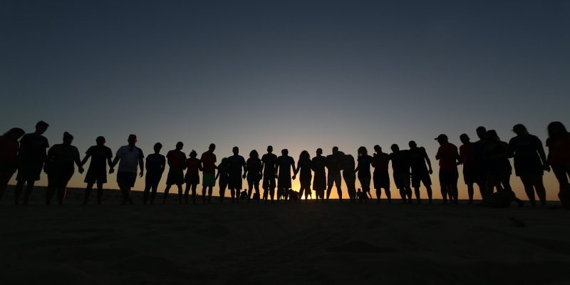 Grupo de jovens reunidos ao ar livre em um momento de convivência e oração, associado a uma comunidade religiosa.